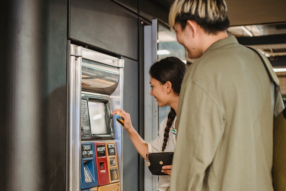 Young couple smiles while purchasing tickets at a station vending machine.
